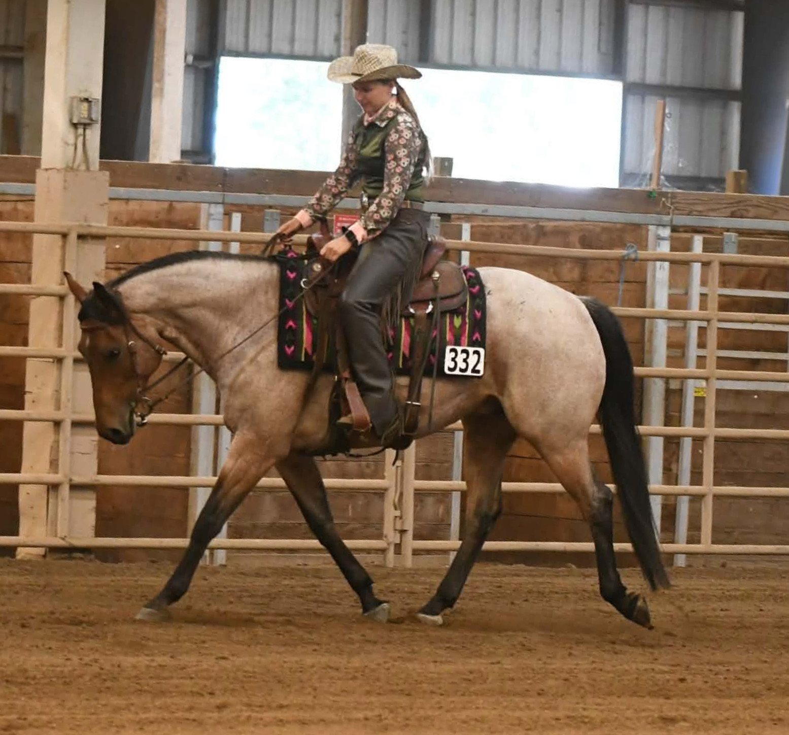 Ali Patton riding a roan horse through an indoor arena
