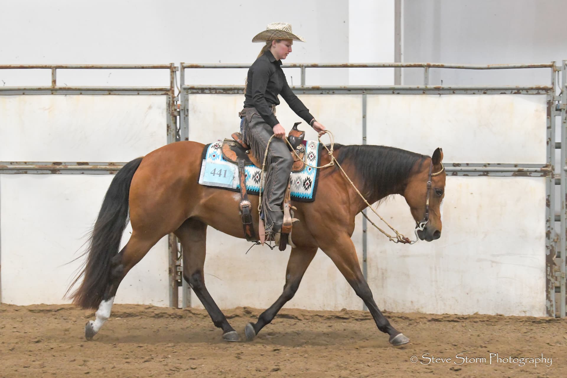 Rider on a bay horse walking on a quiet rein in a show arena